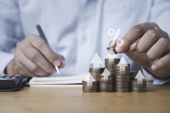 Homme comptant des pièces de monnaie avec un bloc-notes et une calculatrice à côté