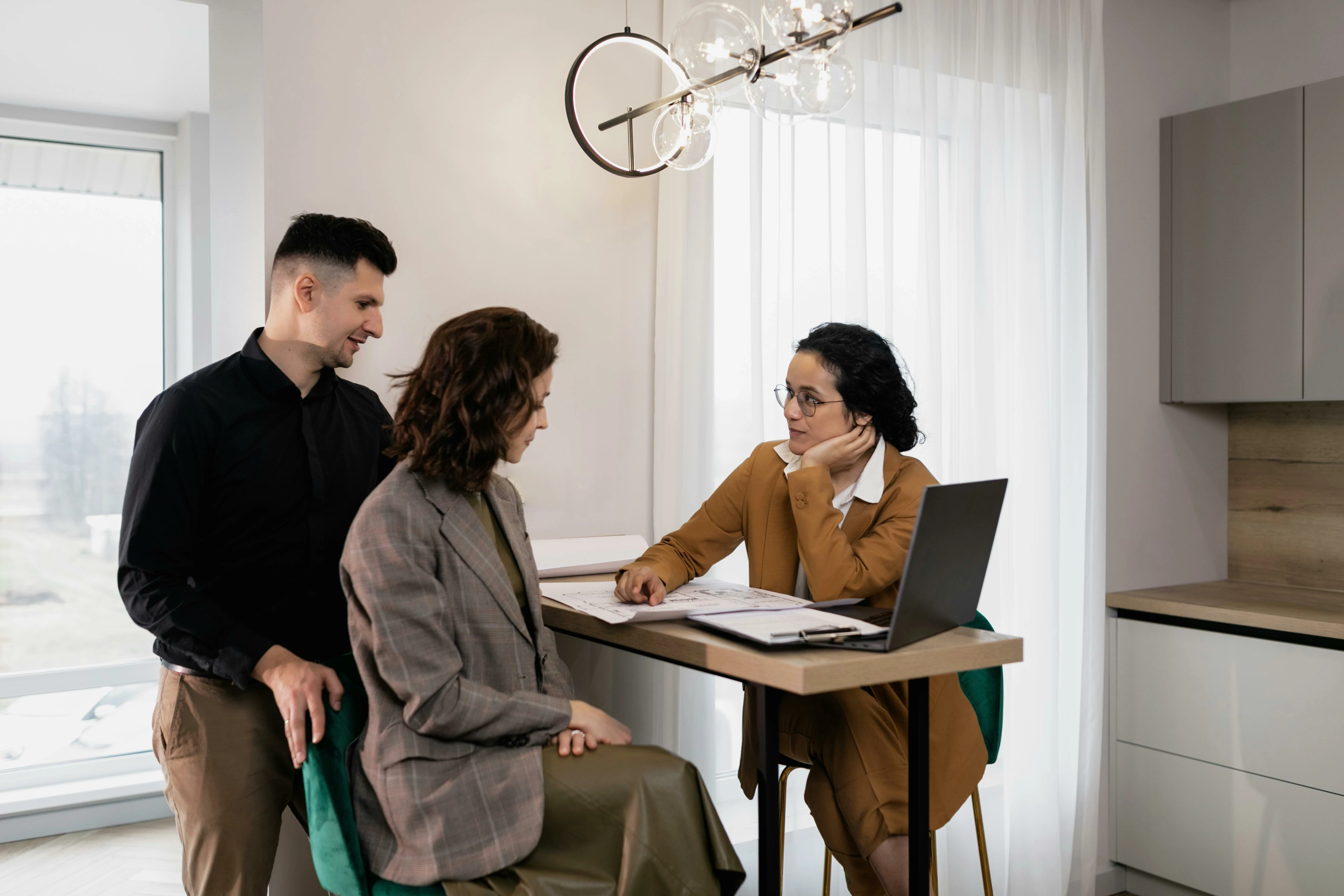 Un couple consultant des documents devant une professionnelle de l'immobilier.
