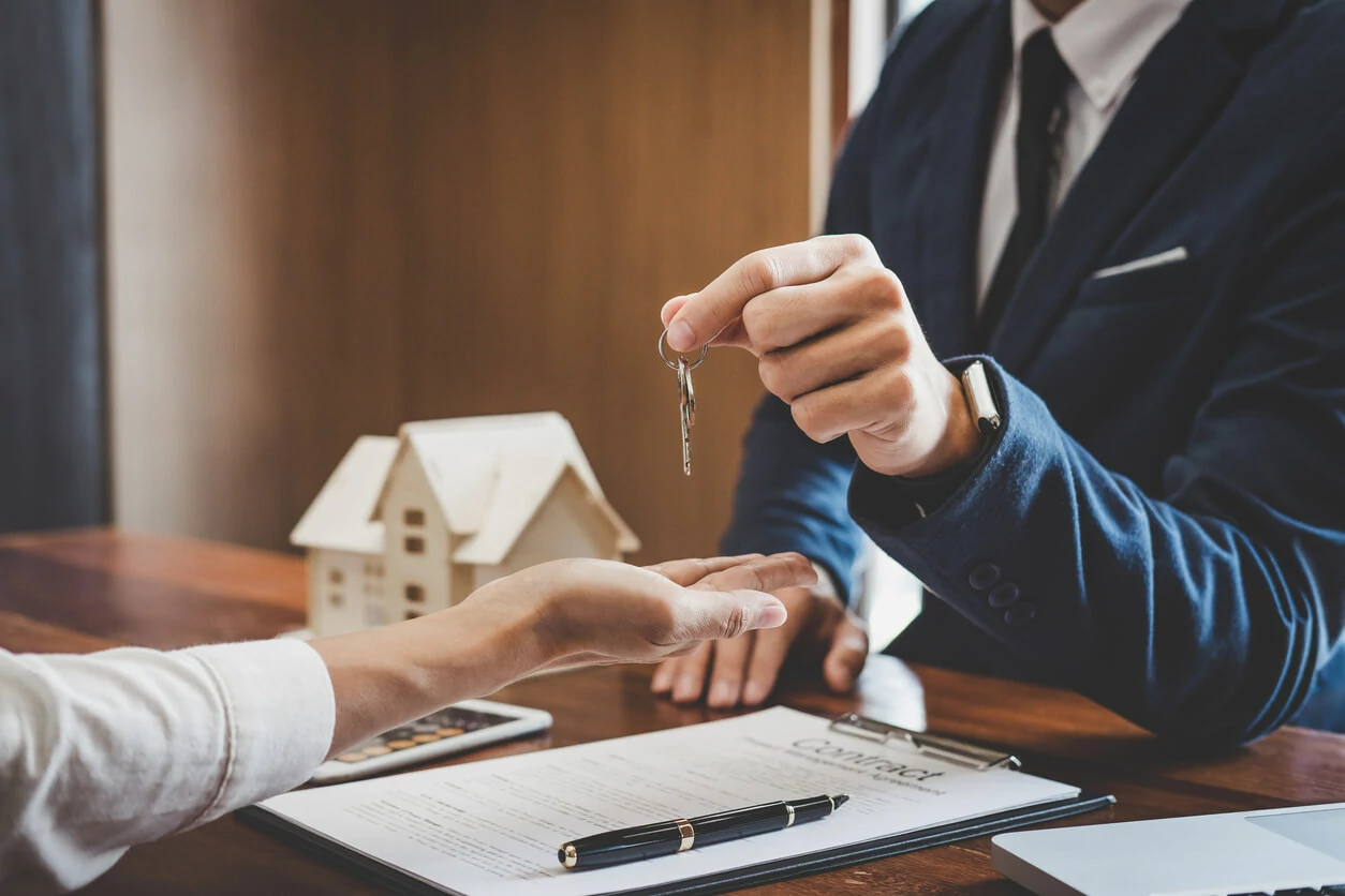 Main tenant une clé et une autre main tendue pour la recevoir.