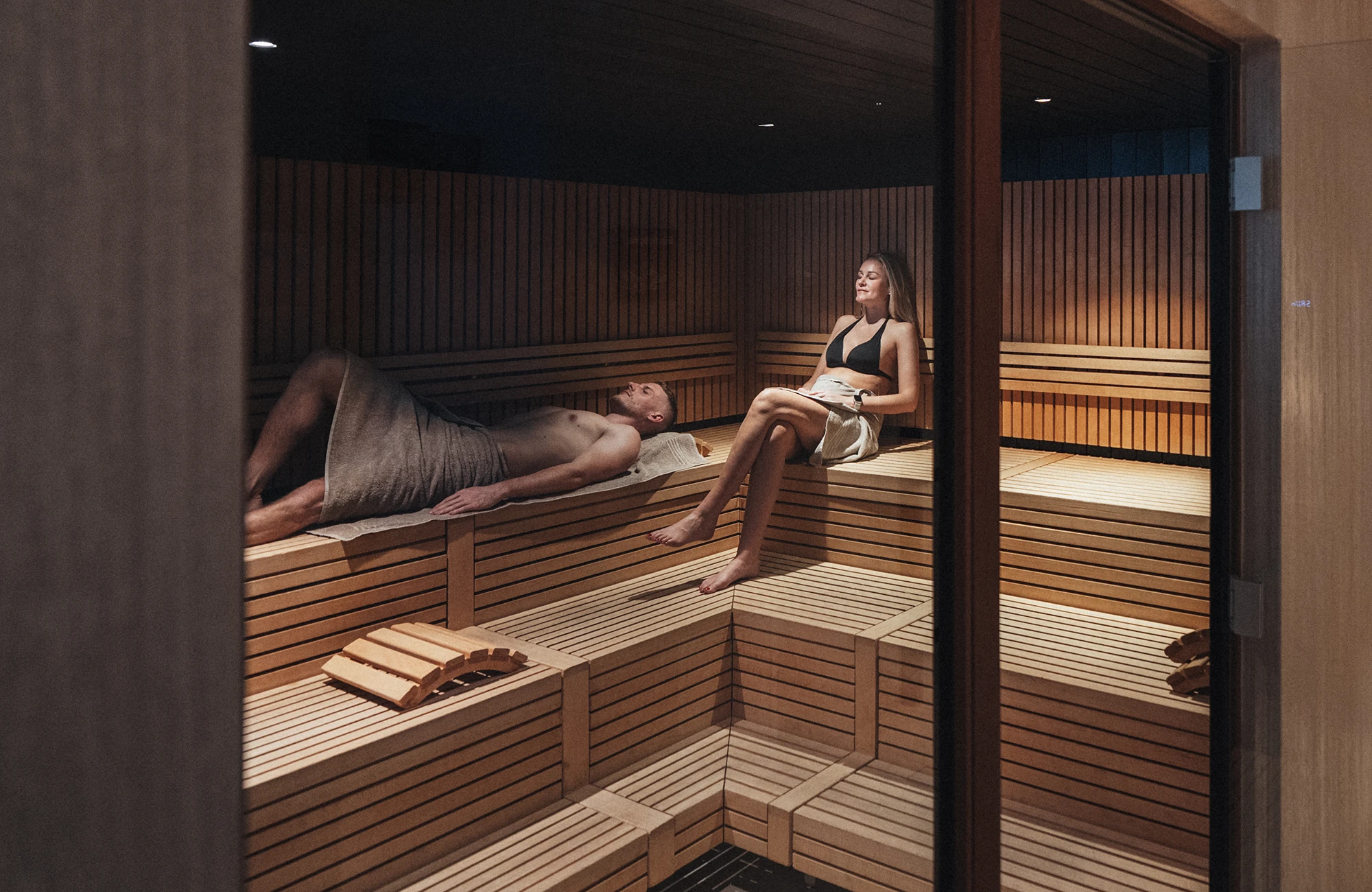 Zwei Gäste ruhen in der Sauna aus Holzlatten