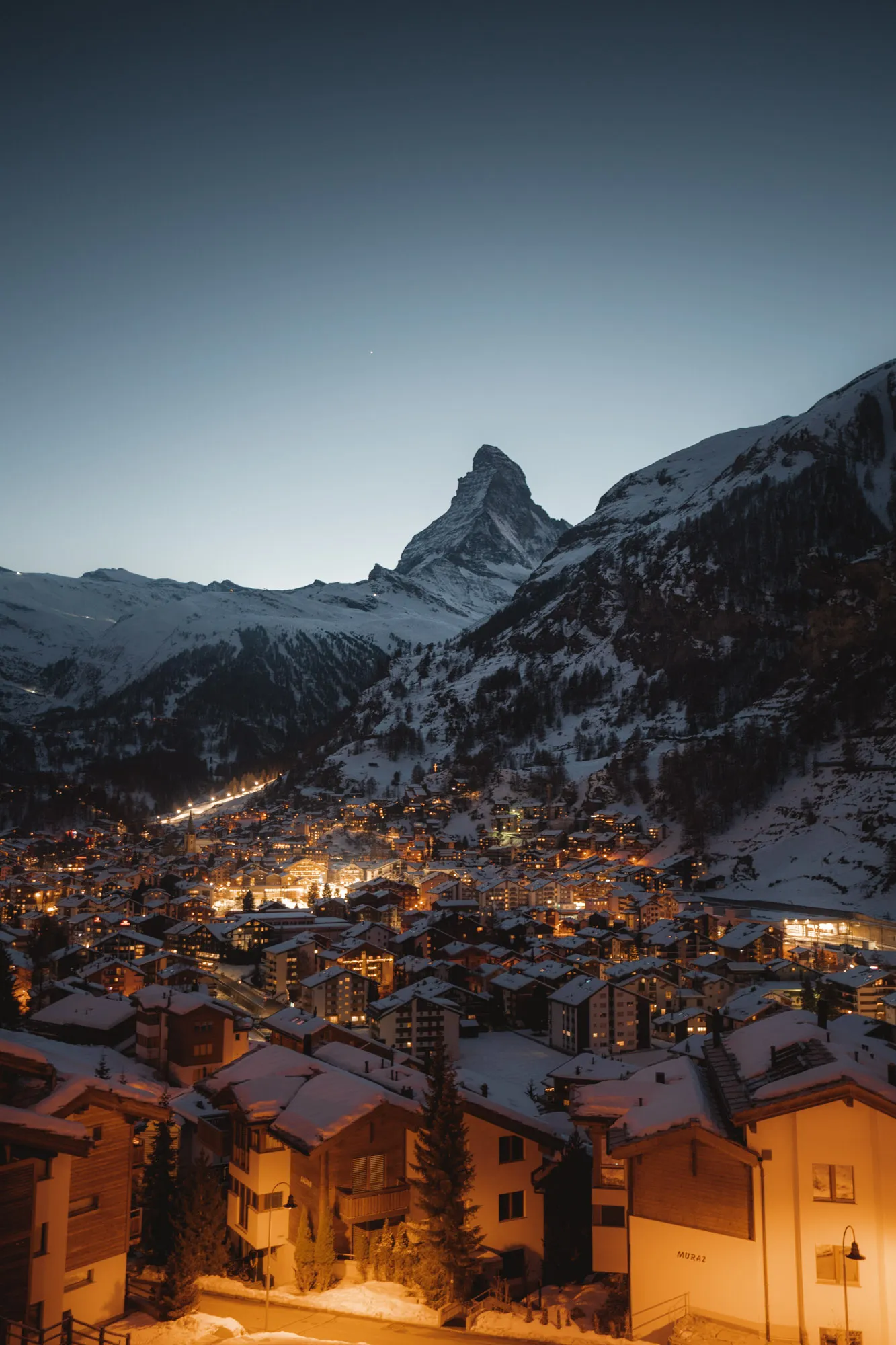 Zermatt bei Dämmerung mit beleuchteten Häusern und Matterhorn