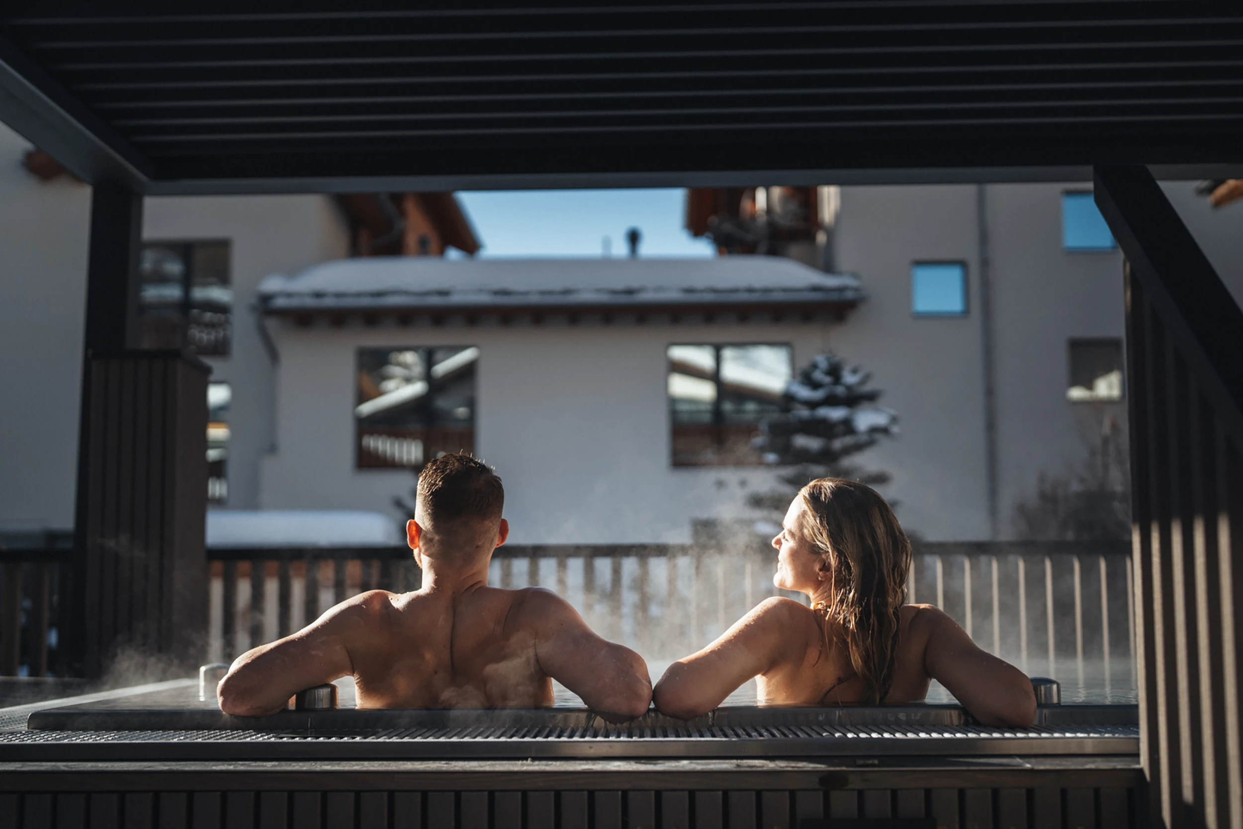 Paar entspannt im Aussen-Whirlpool mit Blick über verschneite Dächer