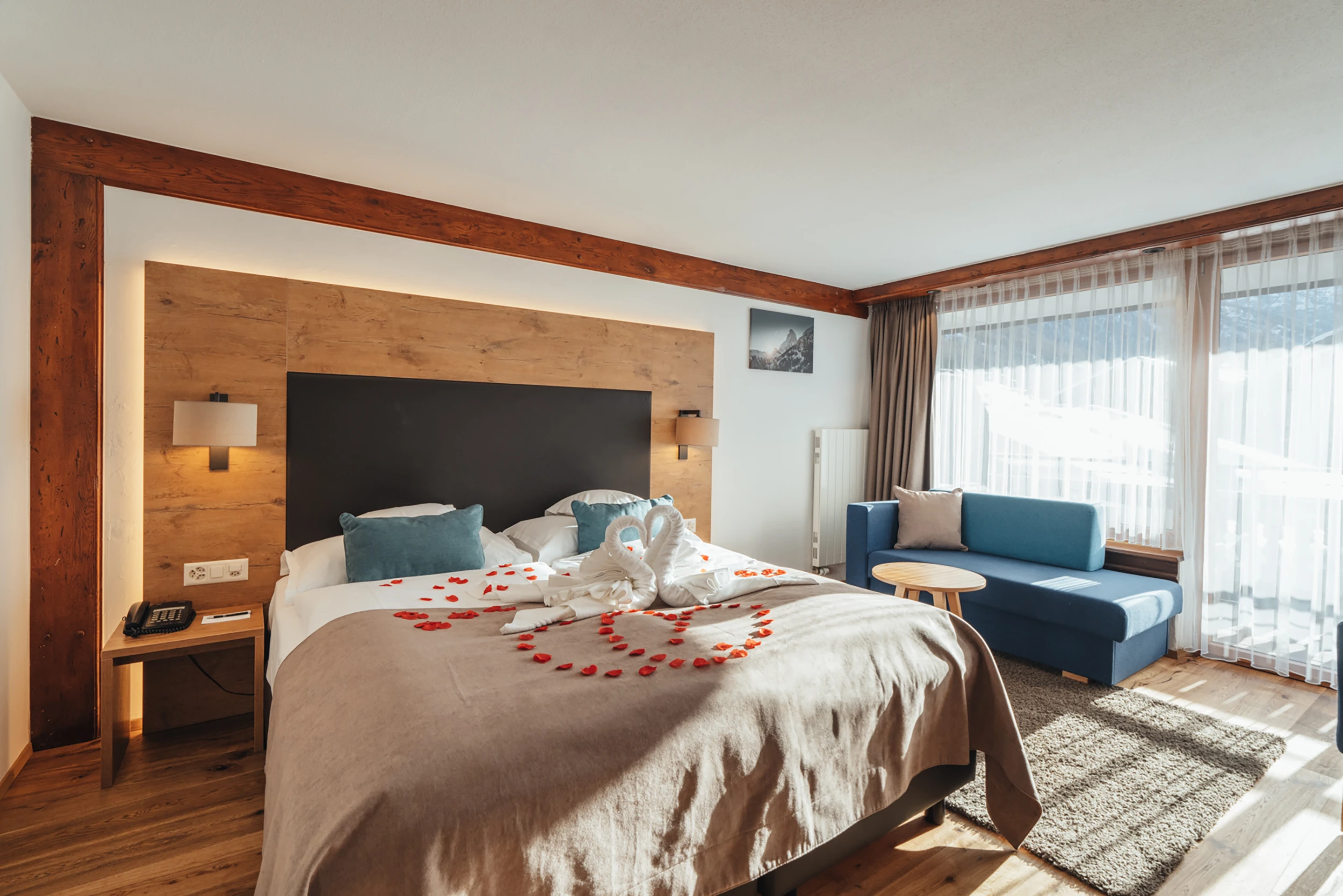 Doppelzimmer mit Holzelementen, blauem Sofa und Balkon
