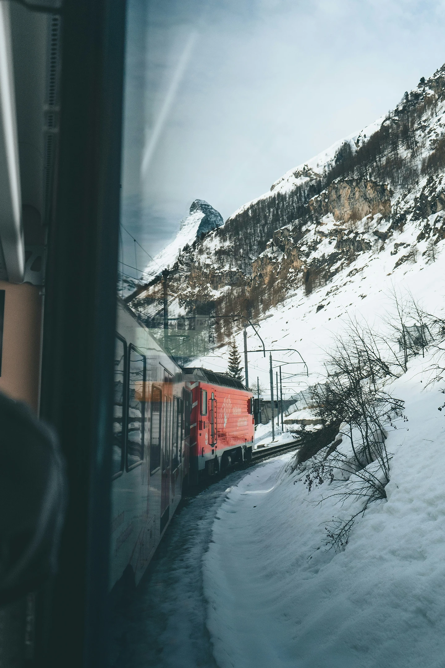 Blick aus dem Zug der Matterhorn Gotthard Bahn auf die verschneite Bergstrecke nach Zermatt