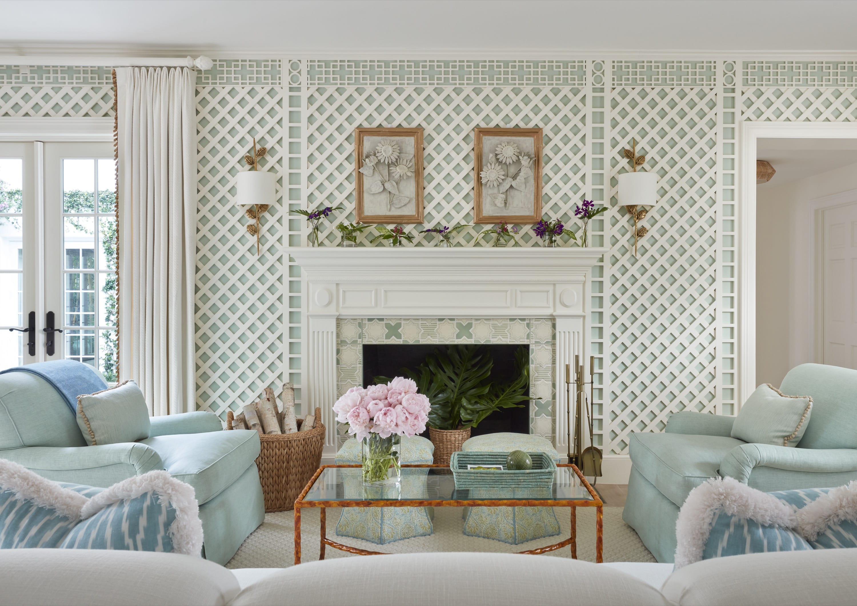 Elegant living room with pale blue armchairs, white fireplace, floral wall art, and glass coffee table.