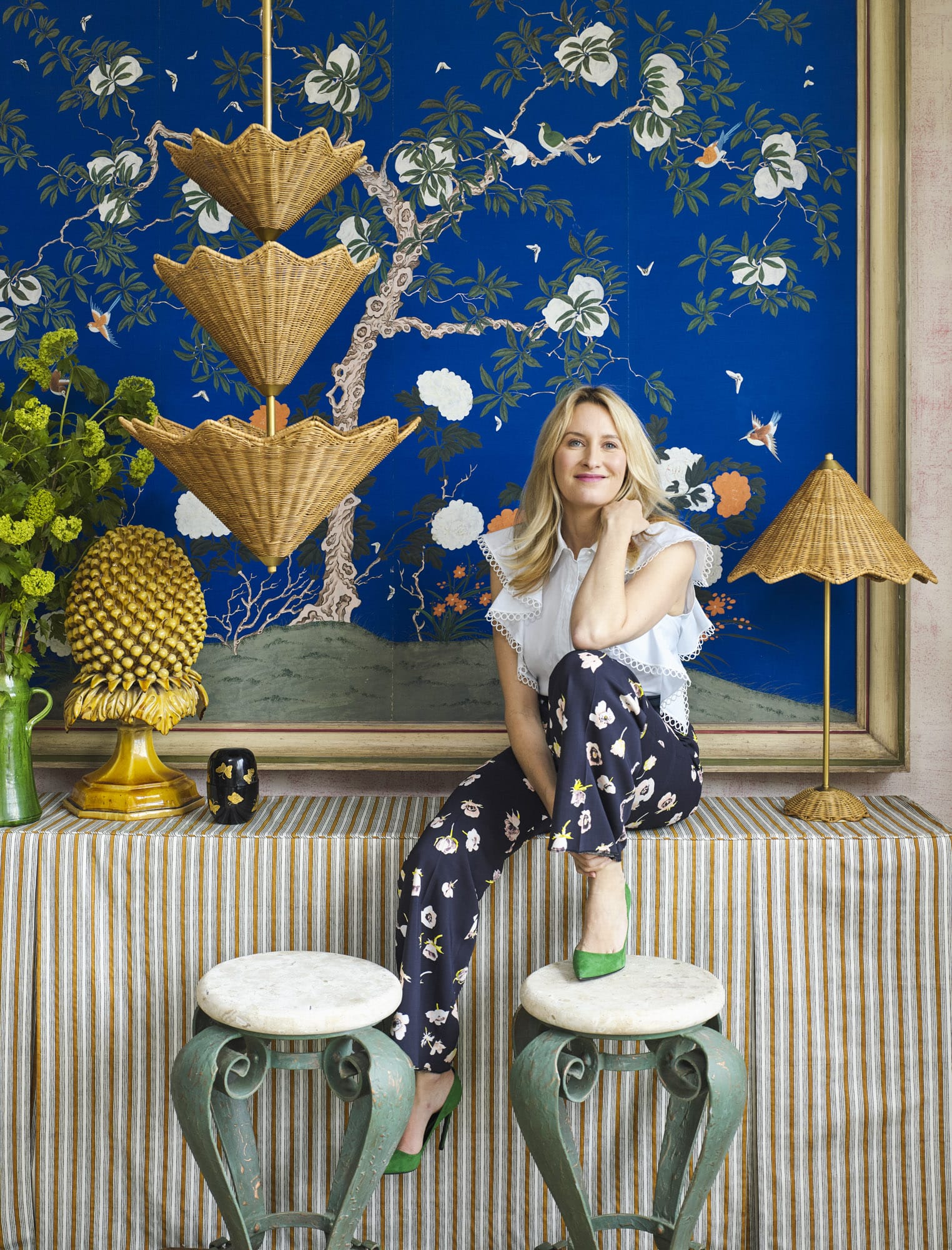 Celerie Kemble sitting on stools against a blue floral backdrop.