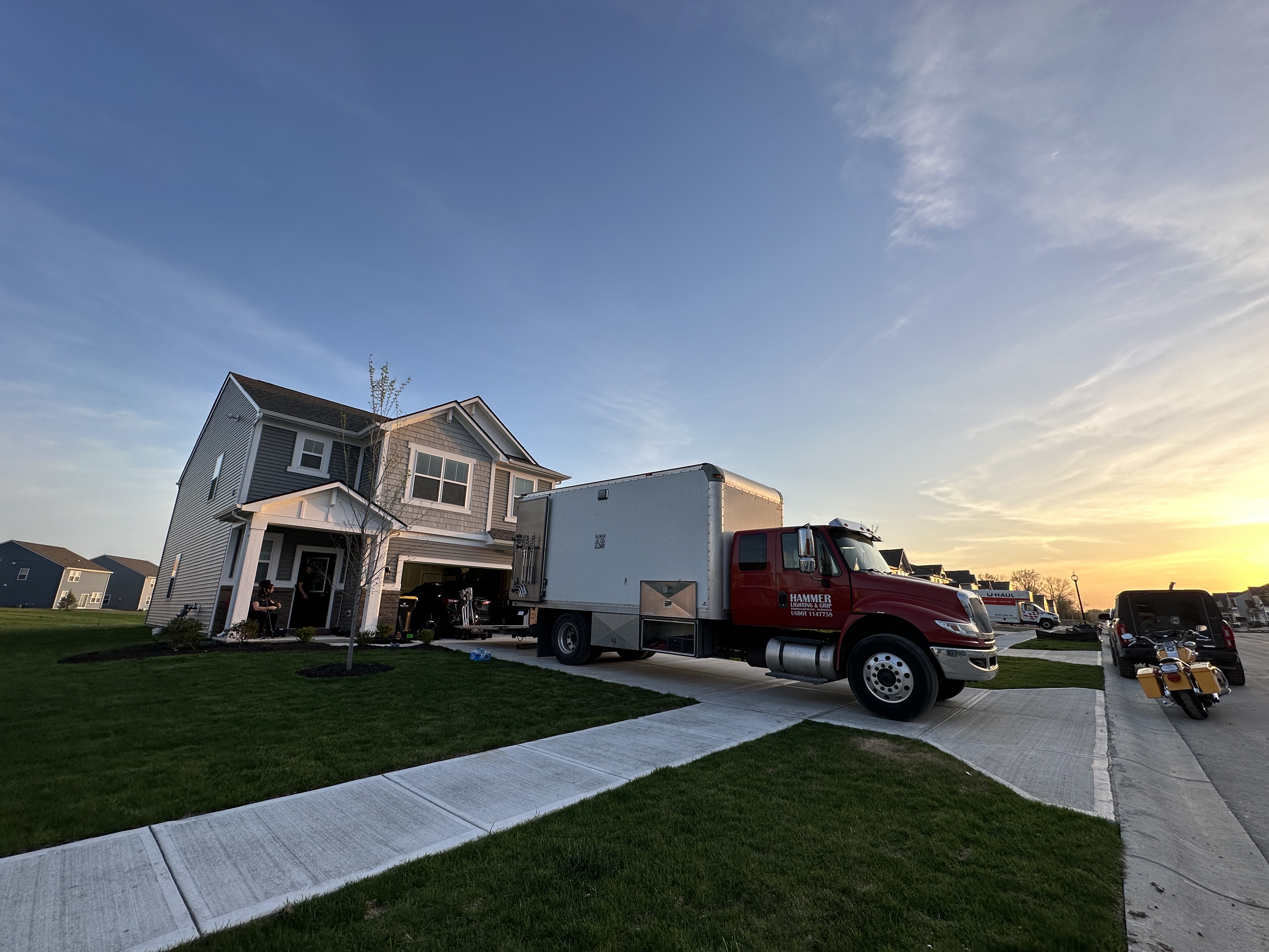 	Suburban house at sunset with production vehicles parked outside