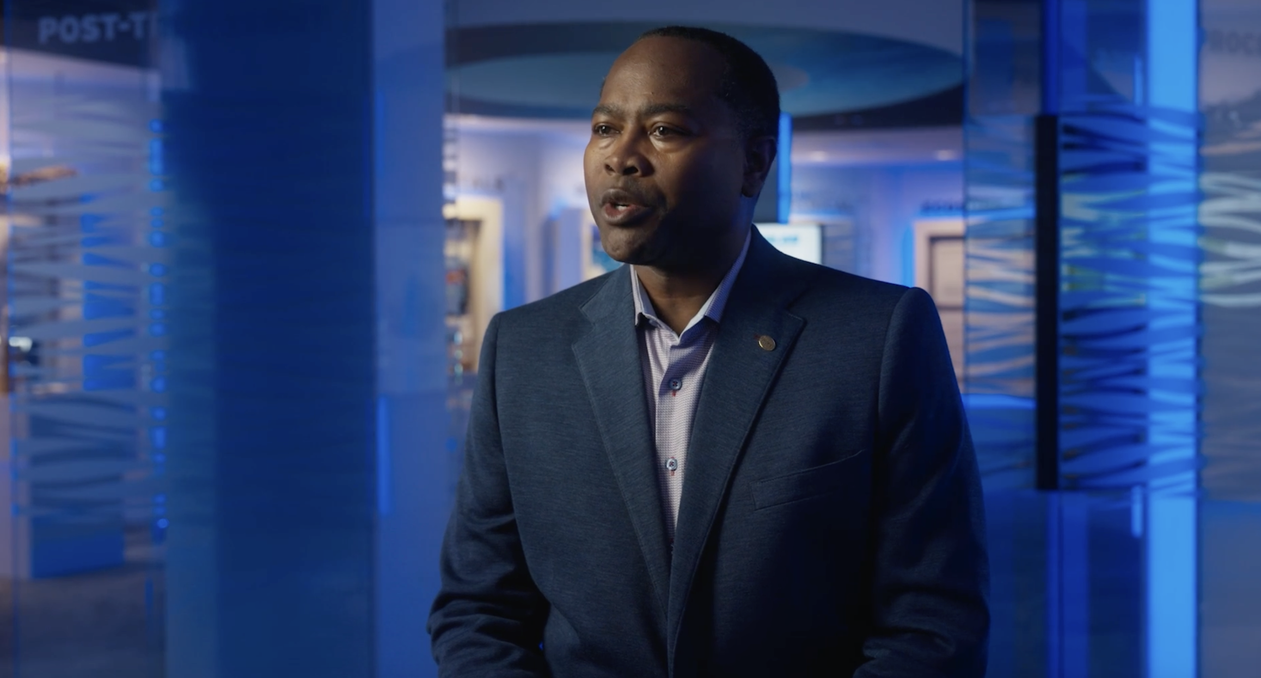 Man in a suit standing in a blue-lit interior