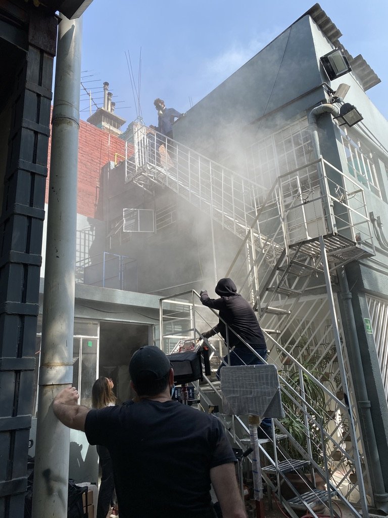 People standing near a building as water sprays into the air