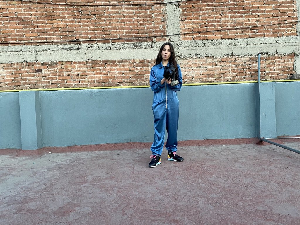 Person standing against a turquoise wall and brick background