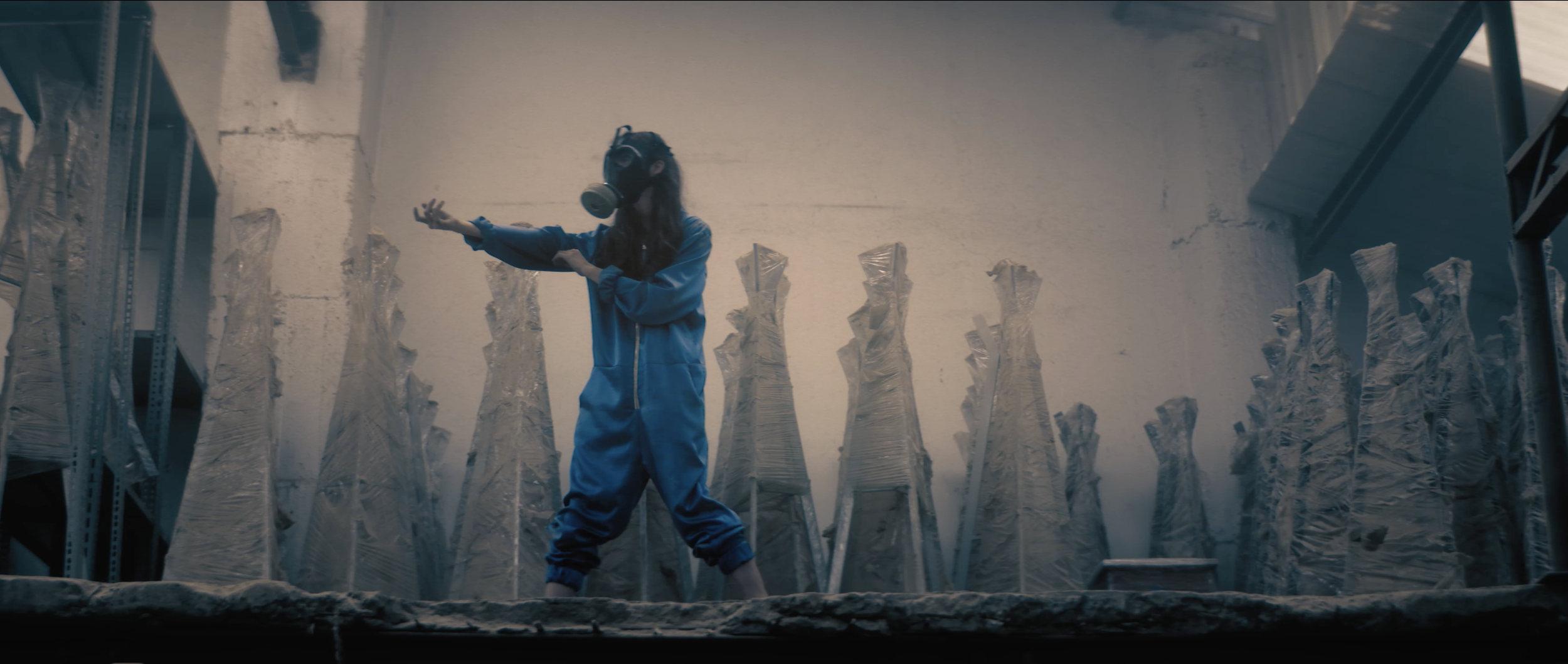 Person standing with arms outstretched in a misty industrial setting