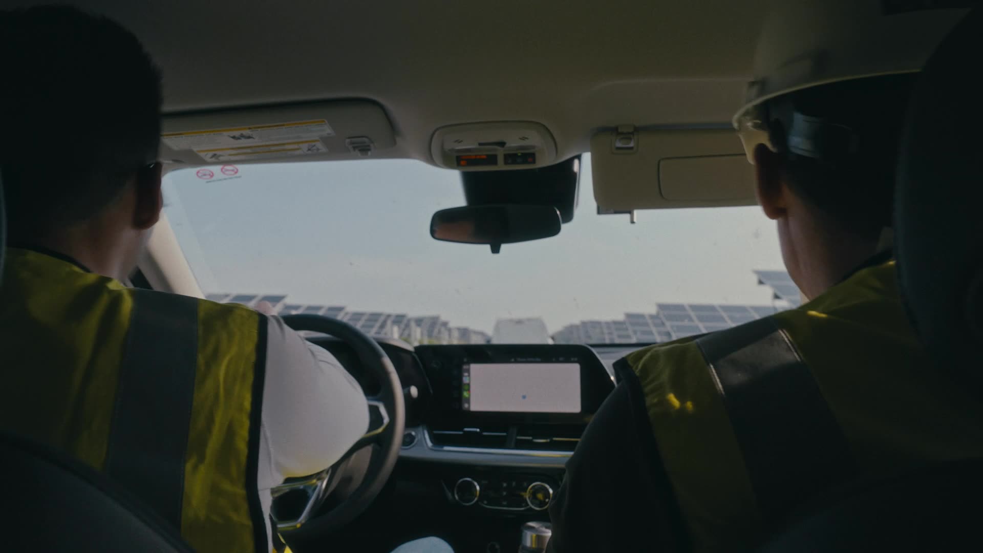 Two workers in safety vests driving through a solar farm