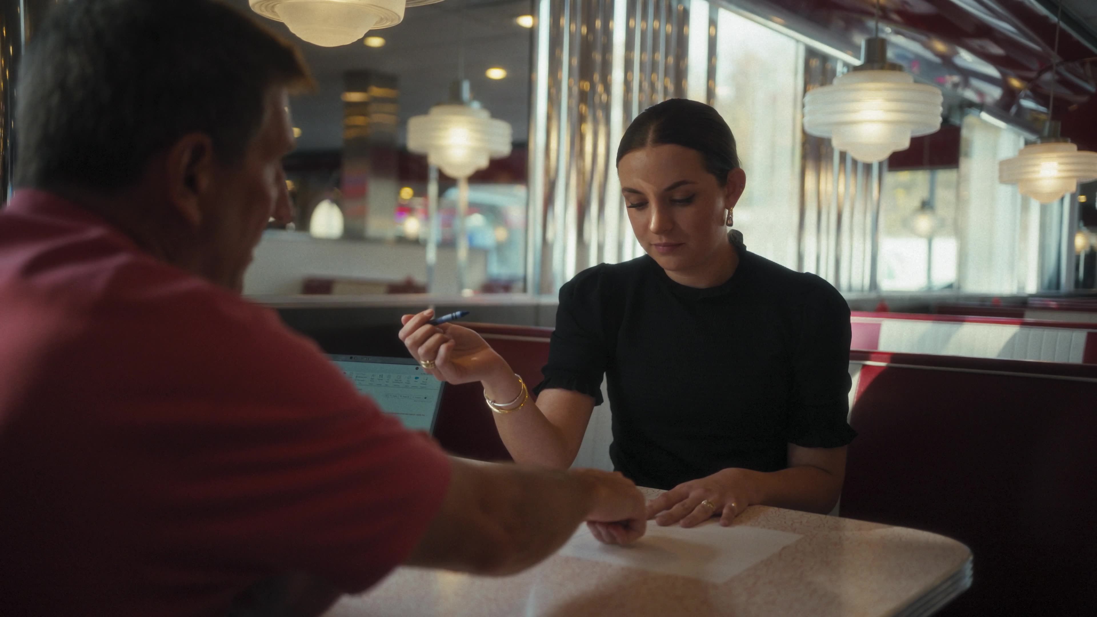 Two colleagues reviewing plans together at a diner table, in a scene from The Adventure Begins