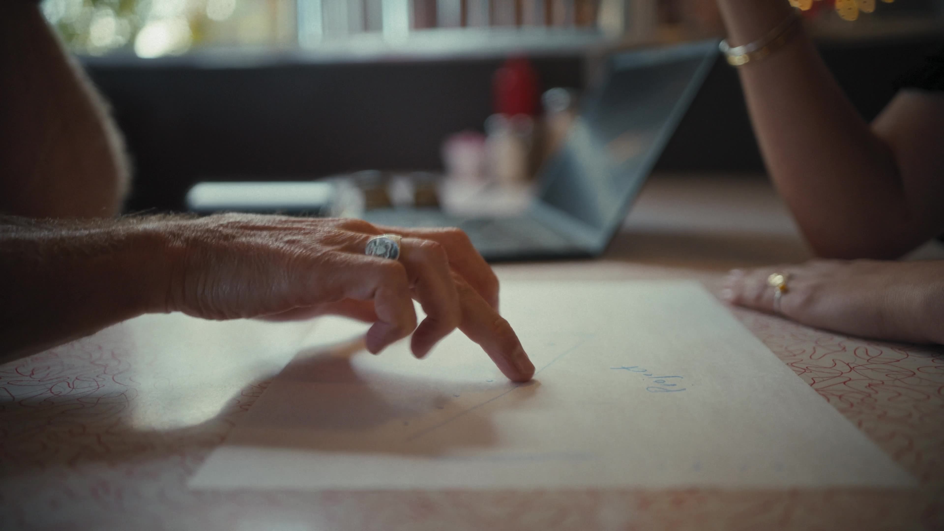 Close-up of a hand pointing to a drawing on paper at a diner table