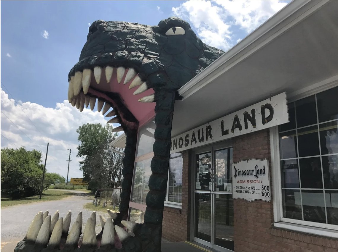 A giant plaster dinosaur head with open jaws over the entrance to Dinosaur Land