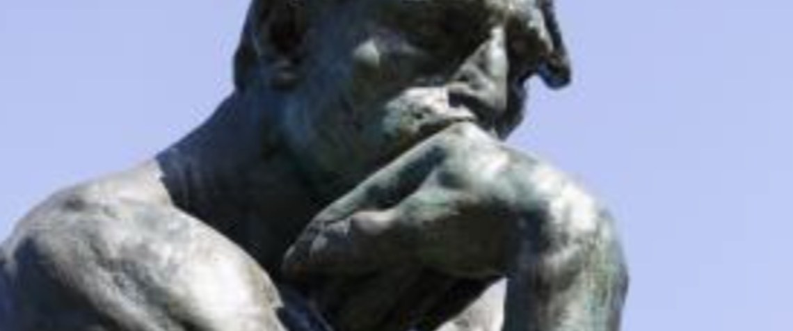 Rodin's The Thinker sculpture against a blue sky
