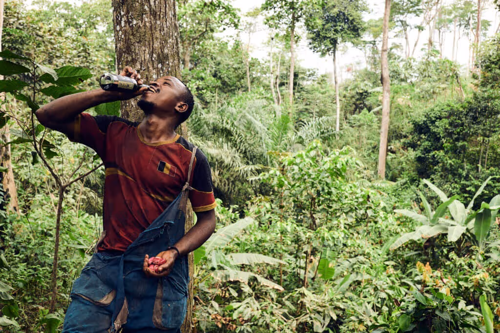 Jean geniesst ein Vivi Kola unter einem Kola Baum