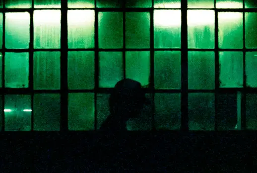 Silhouette of a person in front of a wall of notes, lit green.
