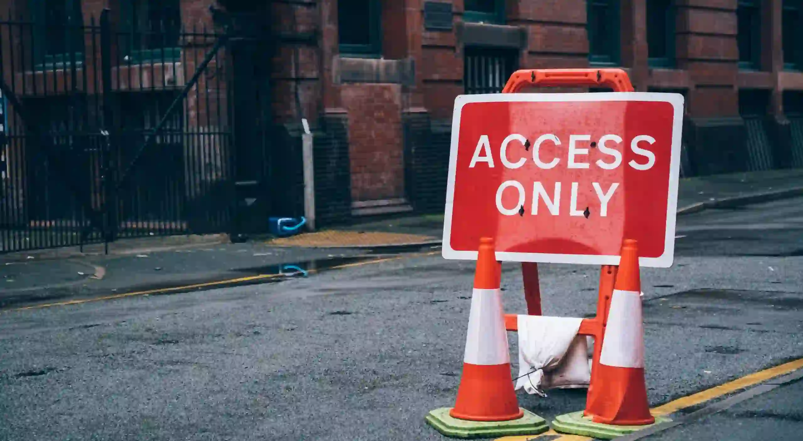Red "ACCESS ONLY" street sign with traffic cones.