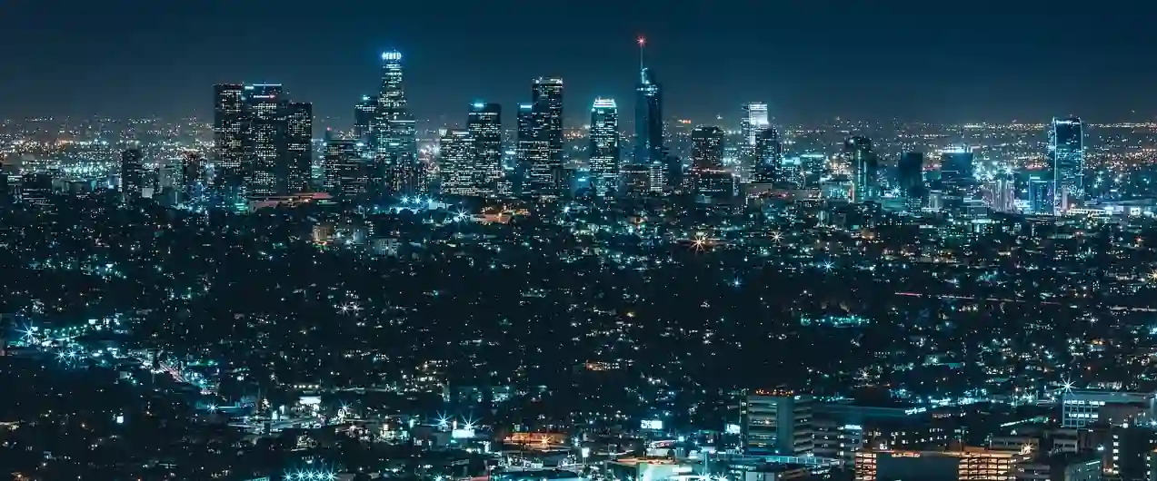 Panoramic view of a city skyline at night with glowing skyscrapers.