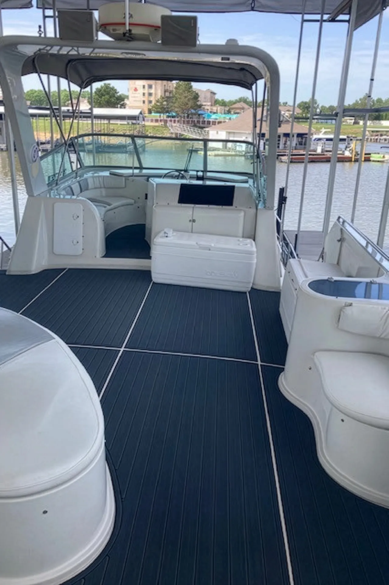 Spacious white yacht deck with navy blue floor, seating areas, and water view in the background.