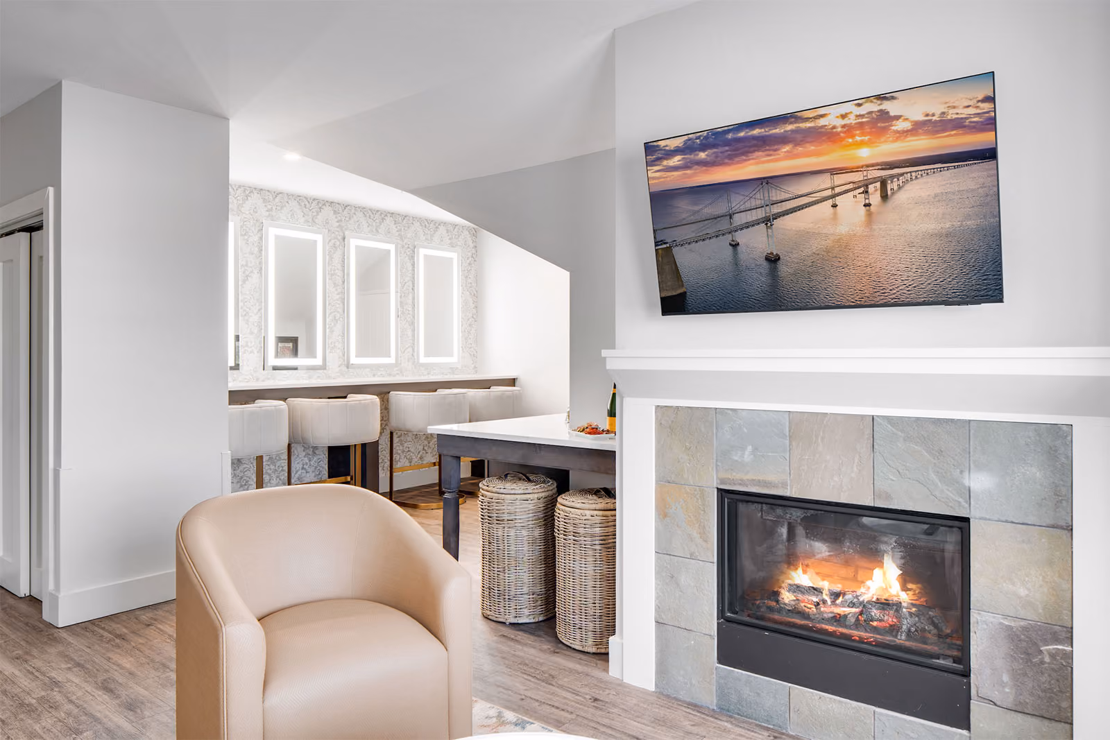 Modern living room with a fireplace, wall-mounted TV, armchair, and bar-style dining area with stools.