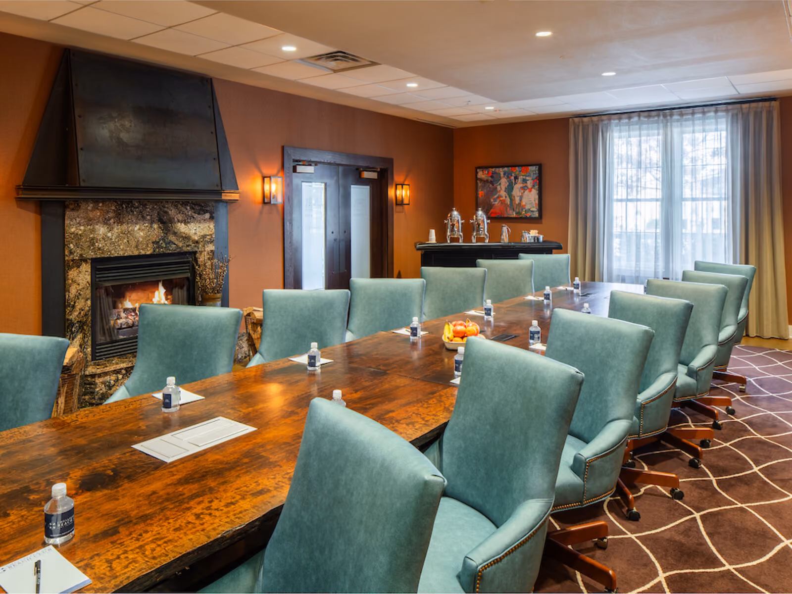 Executive boardroom with long wooden conference table, blue upholstered chairs, and warm ambient lighting at Chesapeake Bay Beach Club
