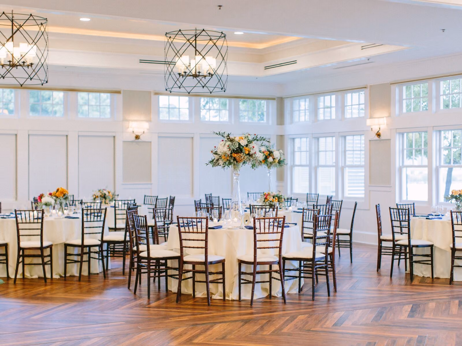 Sunset Ballroom with west-facing bay-view windows, wooden floors, and elegant event setup at Chesapeake Bay Beach Club