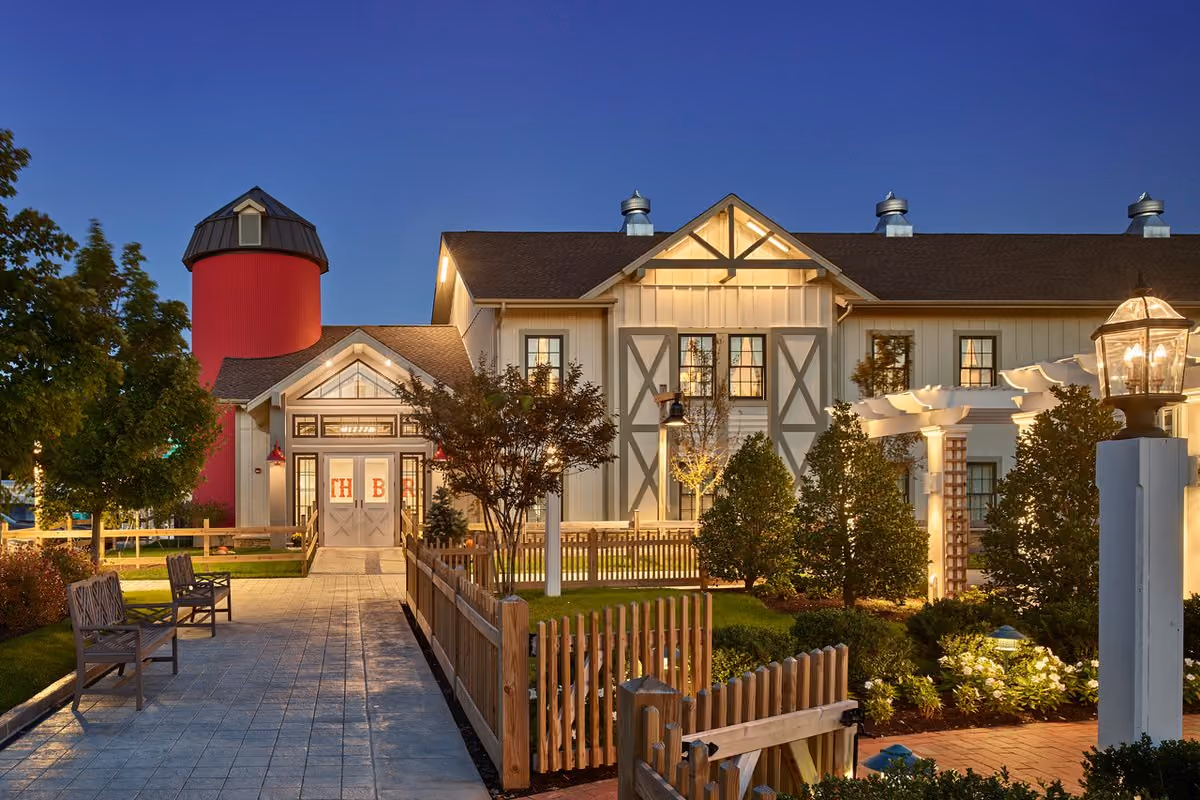 Inn exterior with its signature red silo and landscaped brick walkway illuminated at dusk at Chesapeake Bay Beach Club