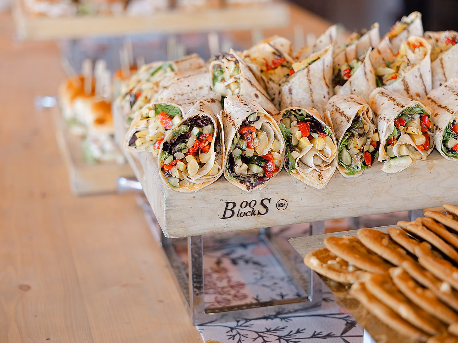 Catered lunch display of gourmet wraps and flatbreads arranged on wooden risers for a corporate event