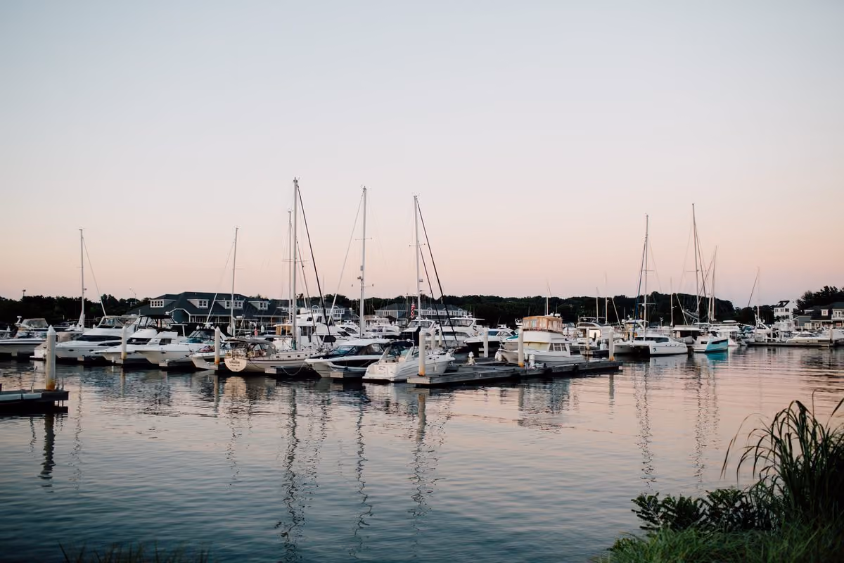 Sailboats moored in the marina at dusk with soft pink sky reflections for a waterfront dock and dine