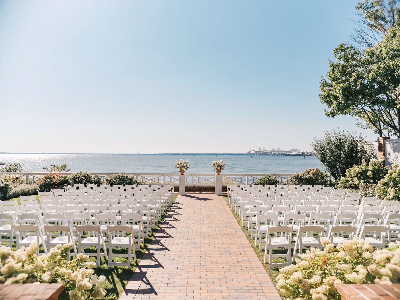 Waterfront wedding ceremony setup with white folding chairs overlooking the Chesapeake Bay