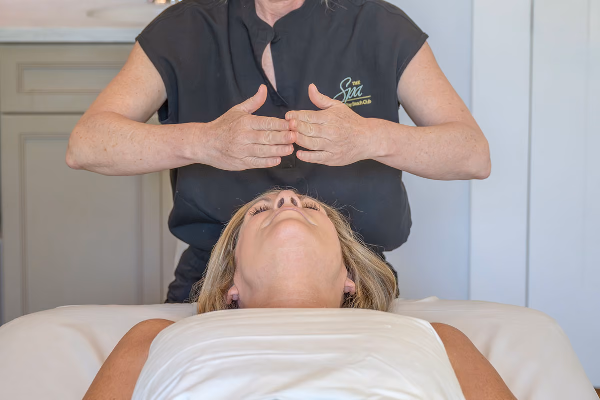 Spa therapist performing a calming facial pressure-point technique on a relaxed client during a body ritual