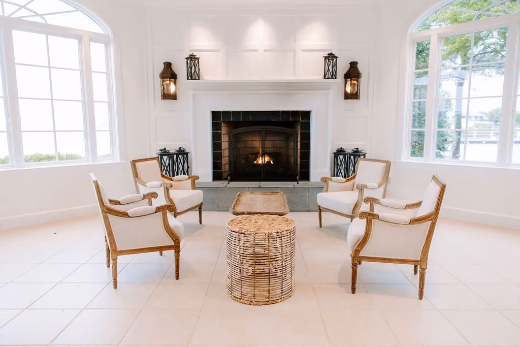 Garden Room fireplace lounge with upholstered armchairs and bay-view windows at Chesapeake Bay Beach Club