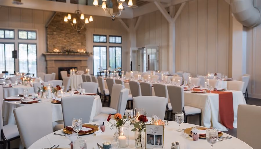 The Inn Ballroom set for a banquet with round tables, autumn runners, and iron chandeliers at Chesapeake Bay Beach Club