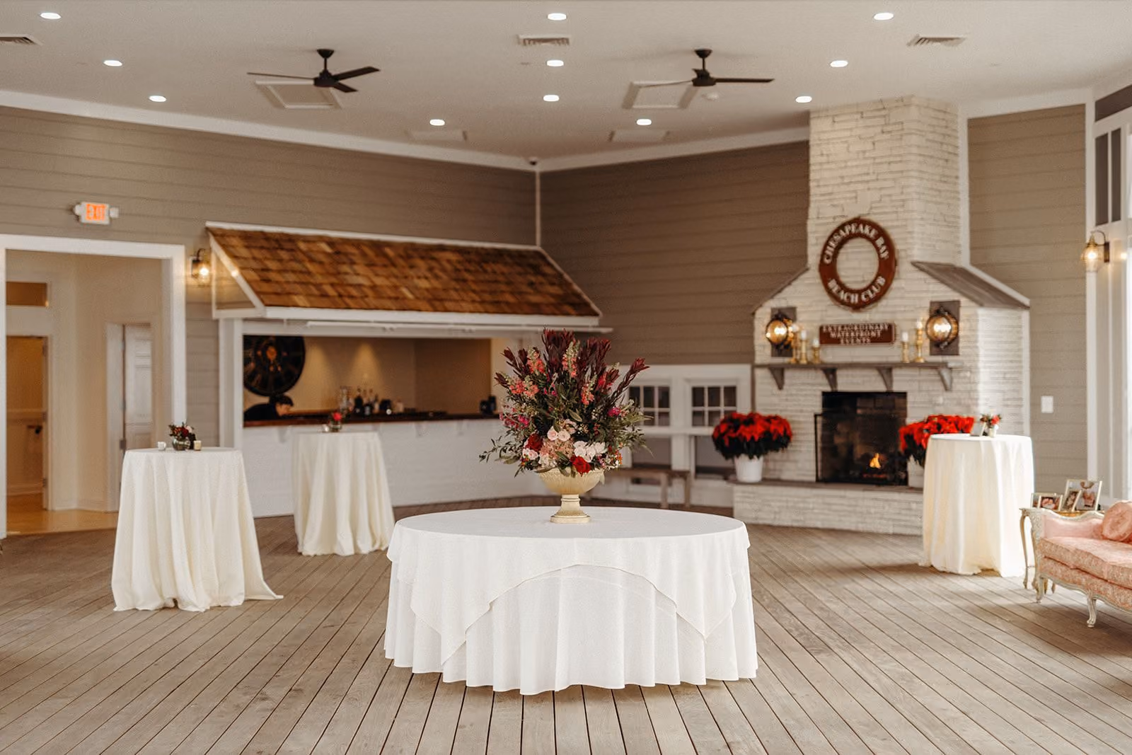 Garden Rooftop with a stone gas fireplace, custom bar, and floral-topped table at Chesapeake Bay Beach Club