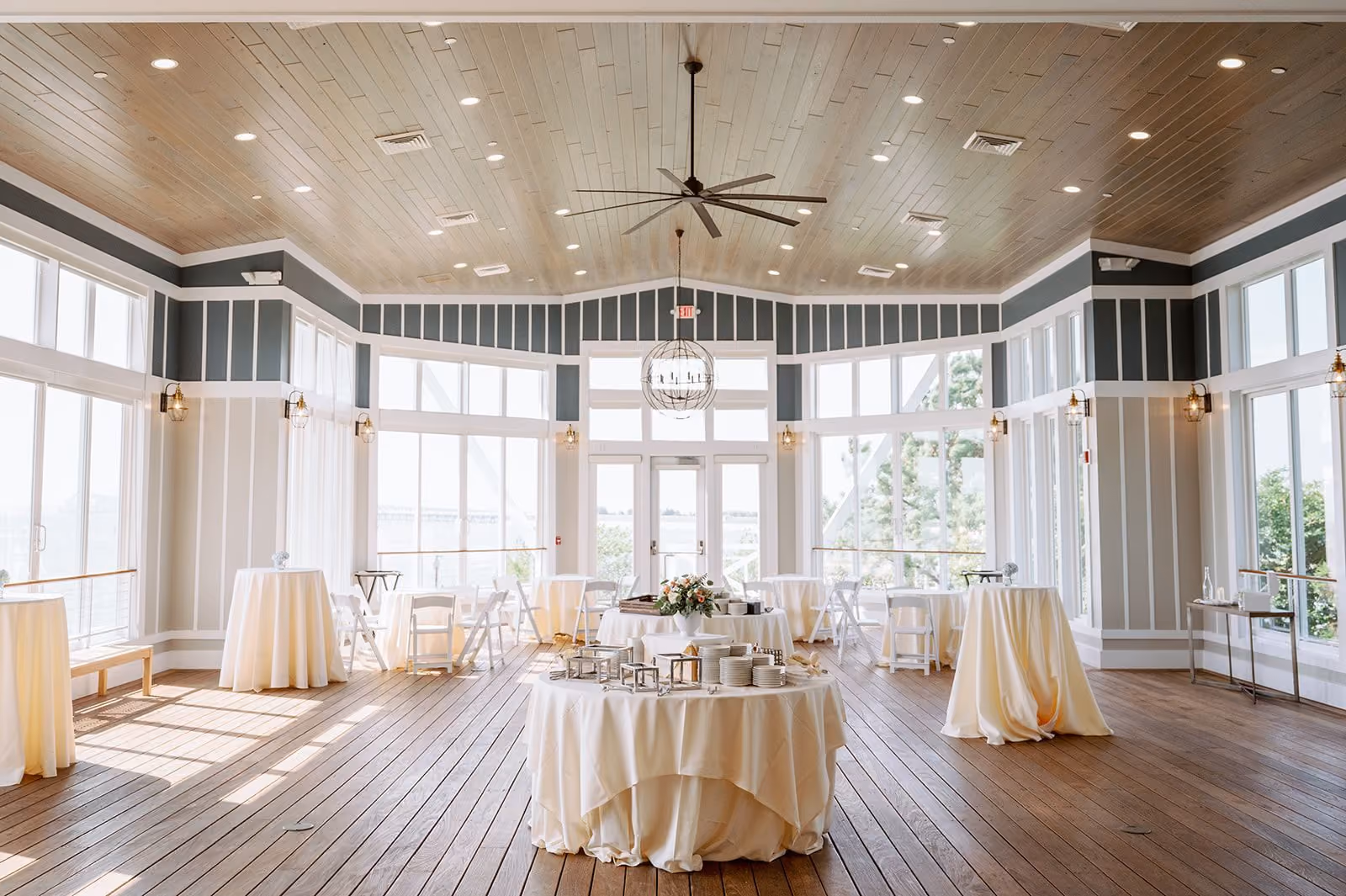 Sunset Ballroom with west-facing bay windows and round tables on a wood floor at Chesapeake Bay Beach Club