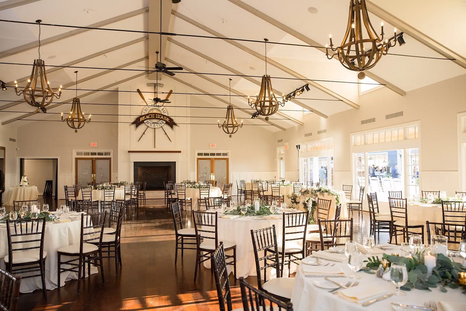 Beach House Ballroom set with round banquet tables under vaulted ceilings and iron chandeliers at Chesapeake Bay Beach Club