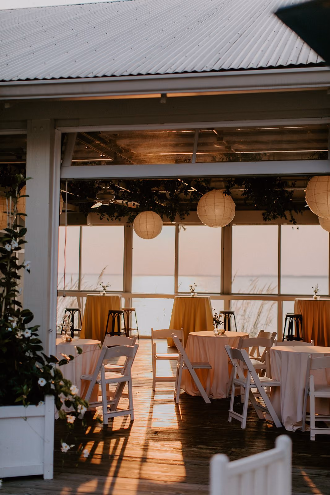 Tavern Bayside with open sliding windows and tables set with orange linens and lanterns at Chesapeake Bay Beach Club