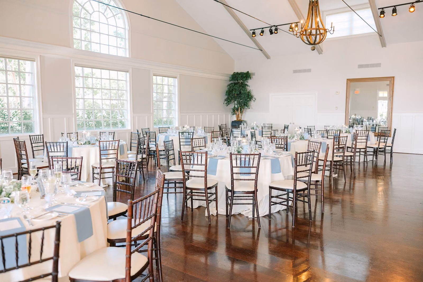 Bright Beach House Ballroom with large windows, greenery, and round tables set for an event at Chesapeake Bay Beach Club