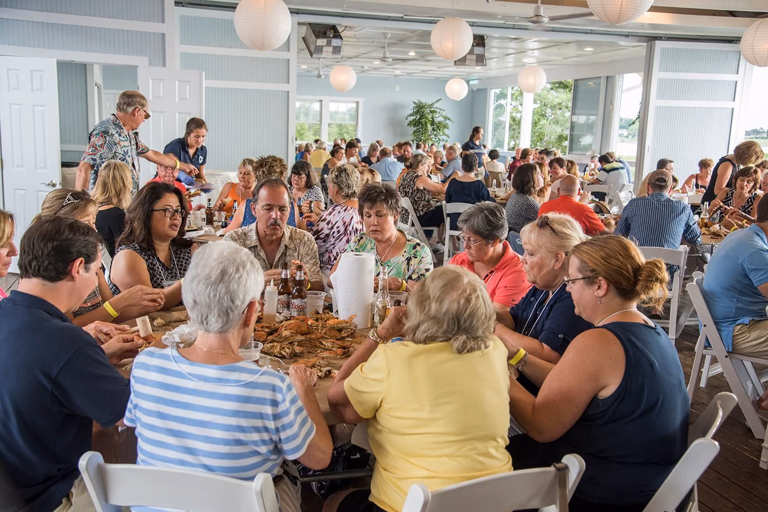 Guests enjoying a crab feast at long tables in Tavern Bayside at Chesapeake Bay Beach Club