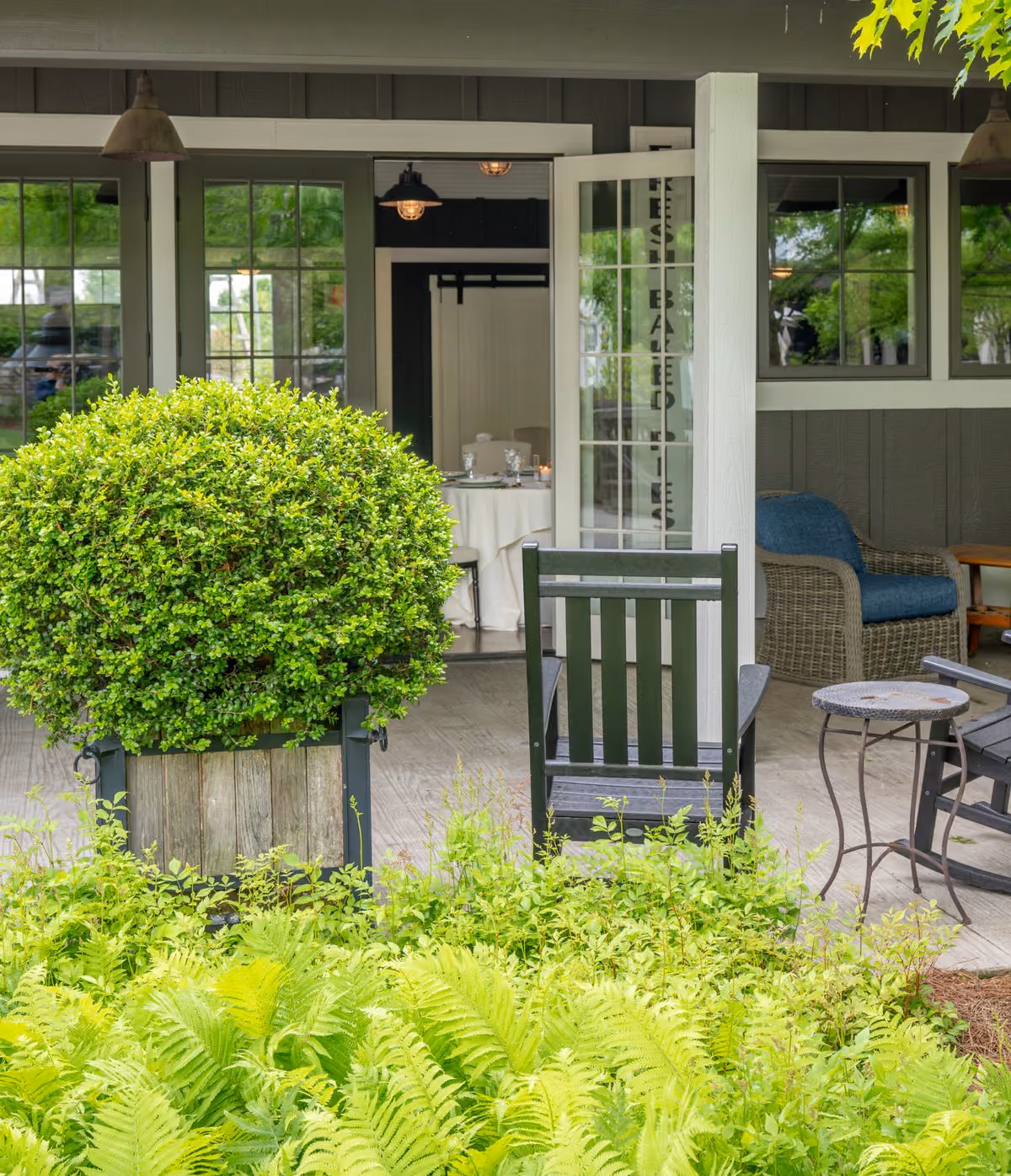Tool Shed garden patio with blue seating and manicured topiary at The Inn at Chesapeake Bay Beach Club