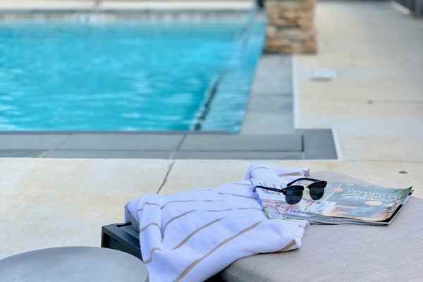 Outdoor resort pools with a pergola, lounge chairs and umbrellas under a blue sky for a spa pool pass