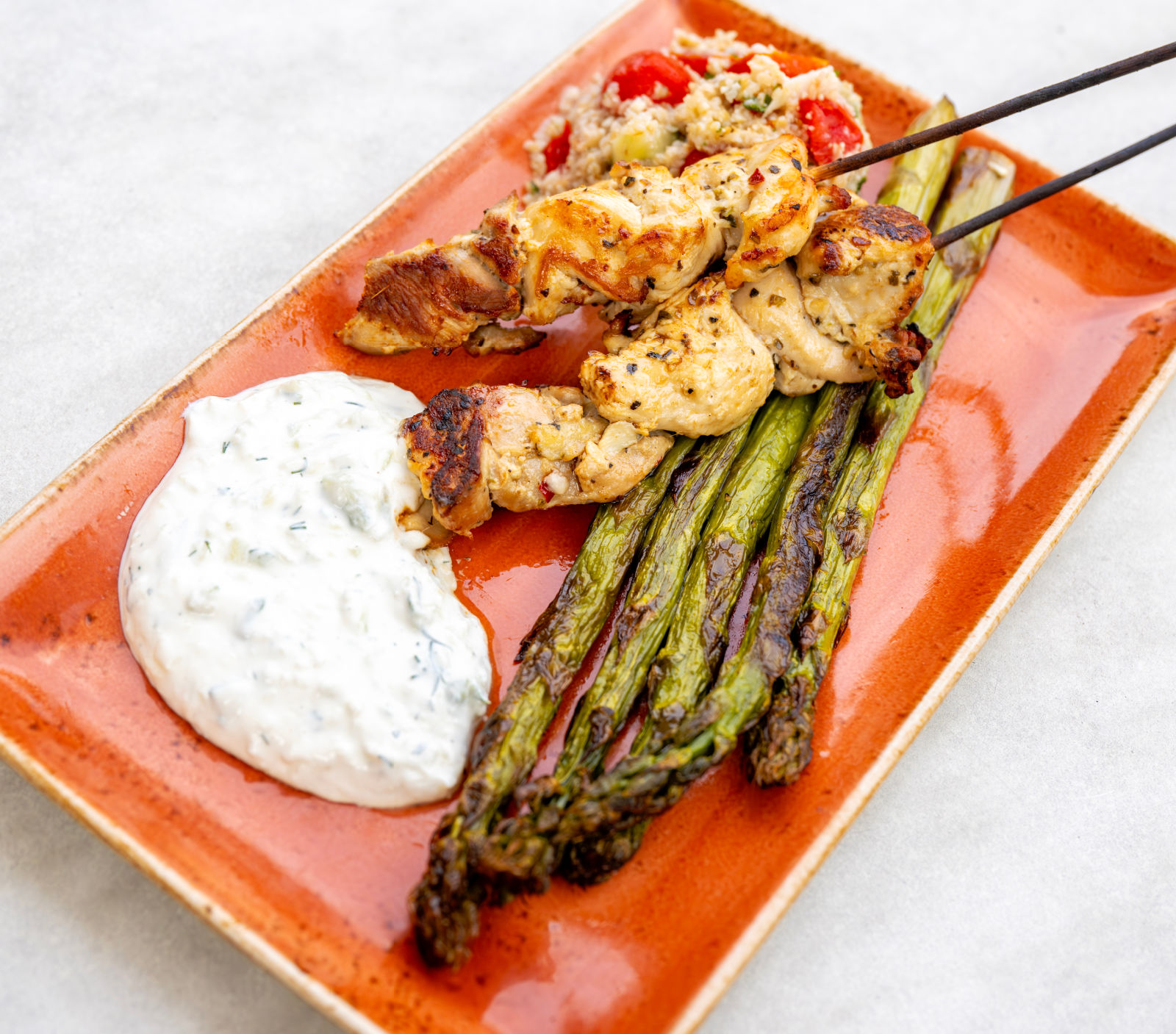 Grilled Chicken Skewers with spiedie marinade, roasted asparagus, cauliflower, tomato and mint tabbouleh, tzatziki sauce