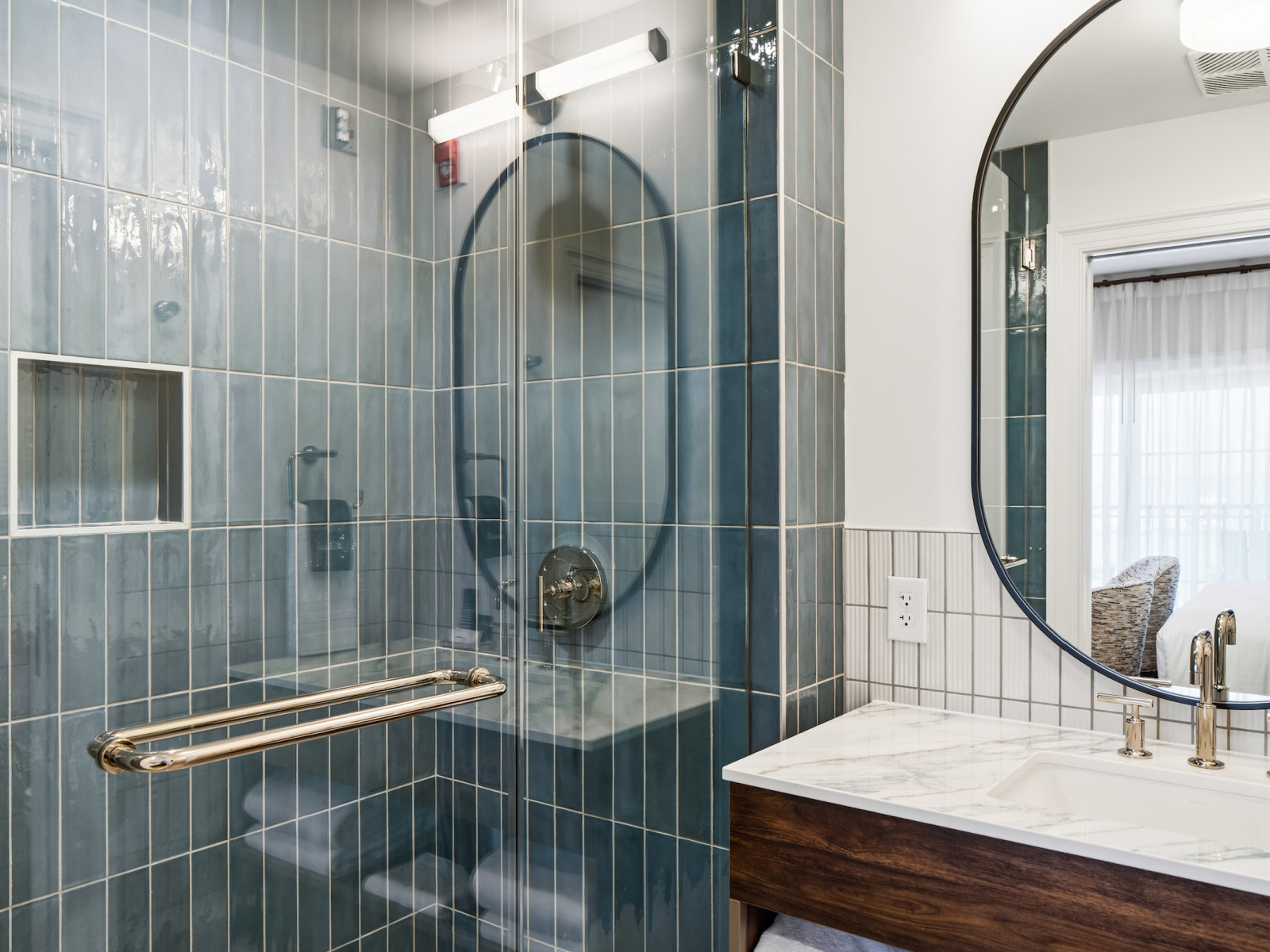 King Premier bathroom at Wilson’s Cove with blue tile walk-in shower, glass enclosure and marble-top vanity.