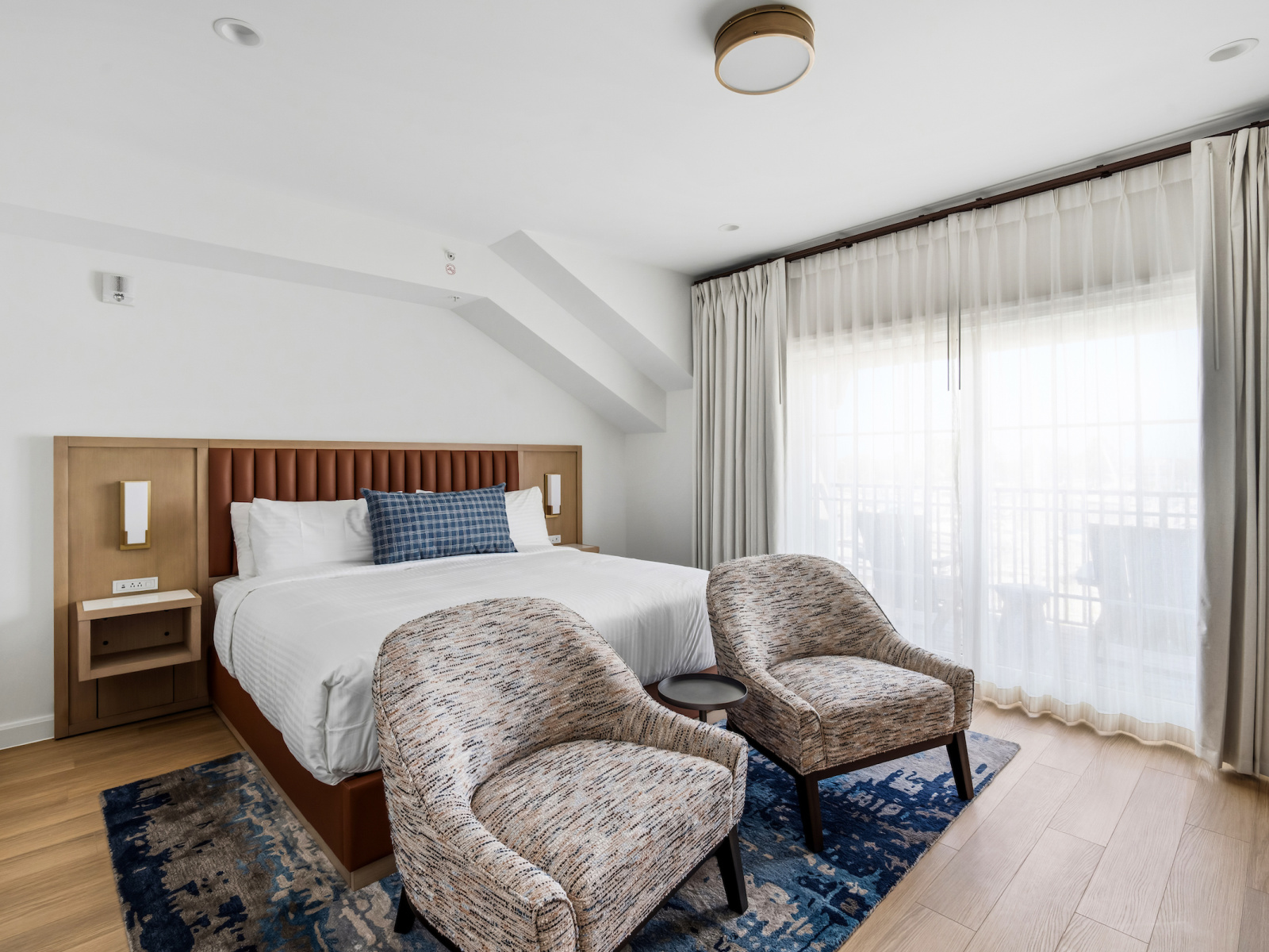 Wilson’s Cove King Premier Guest Room with king bed, coastal seating area and private balcony.