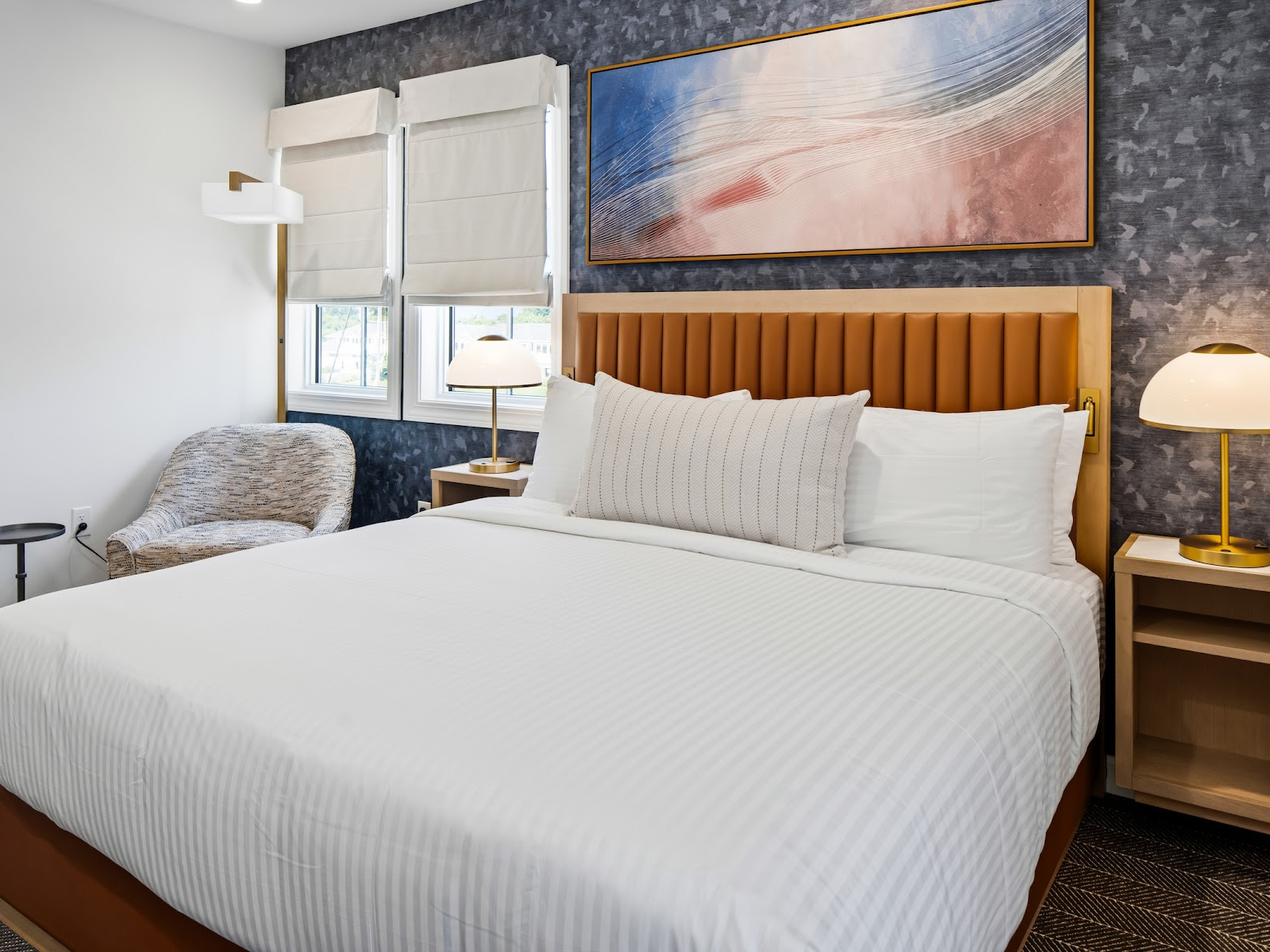 Wilson’s Cove Anchor Suite king bedroom featuring a leather headboard, coastal artwork and comfortable seating.