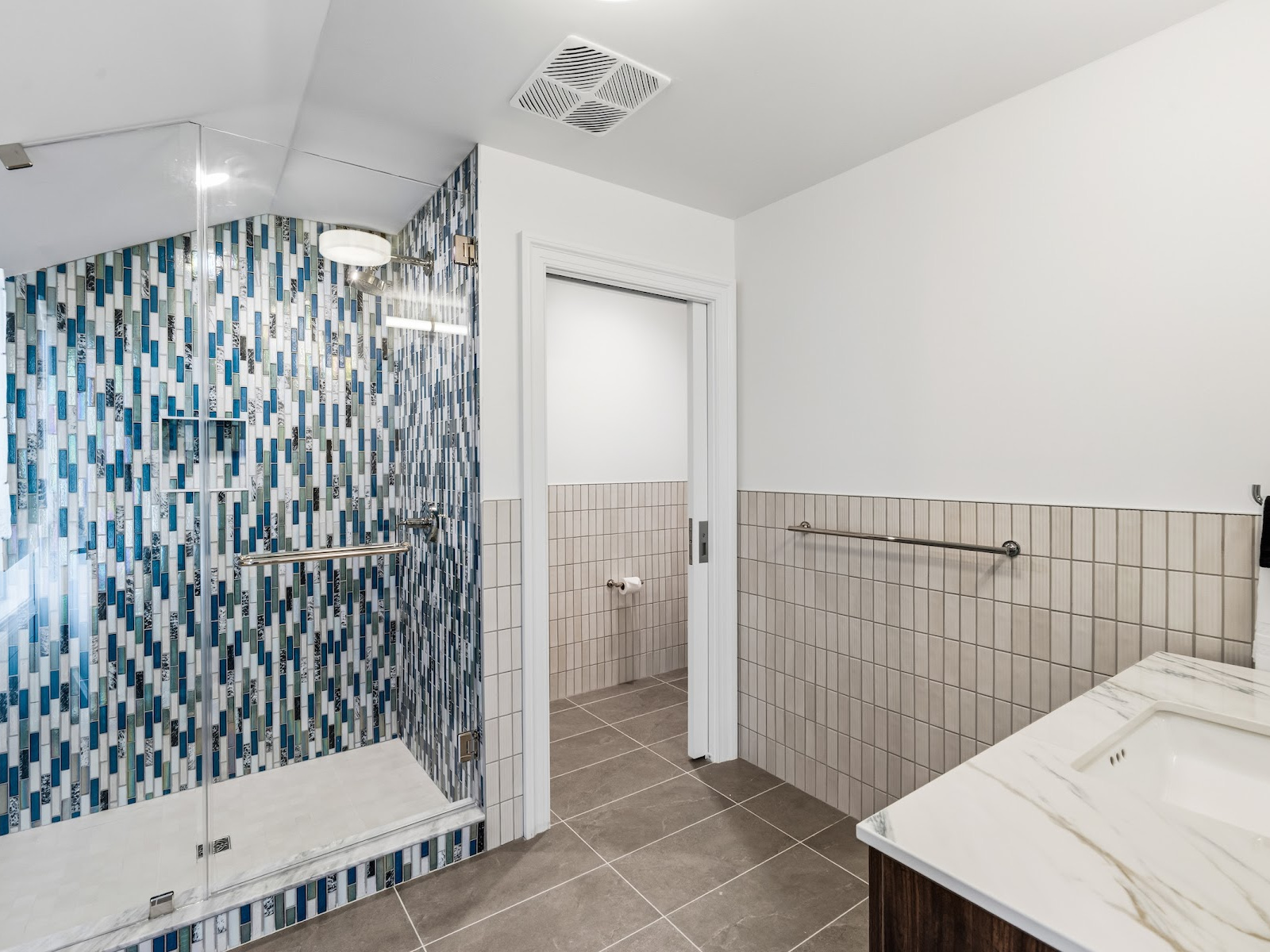 Anchor Suite bathroom at Wilson’s Cove with walk-in shower, blue mosaic tile and marble-top vanity.