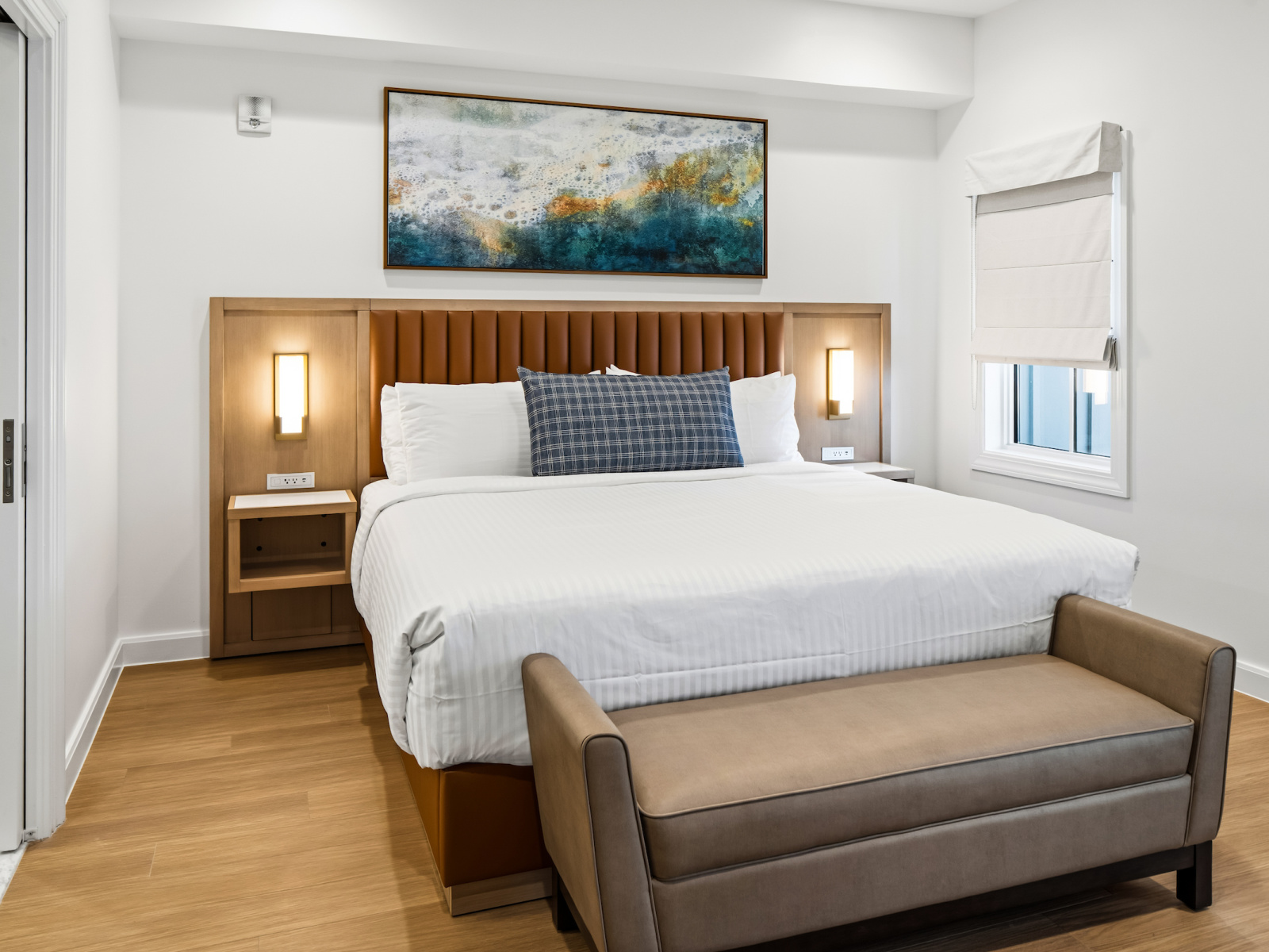 Wilson’s Cove Beacon Suite king bedroom with coastal furnishings and upholstered bench.