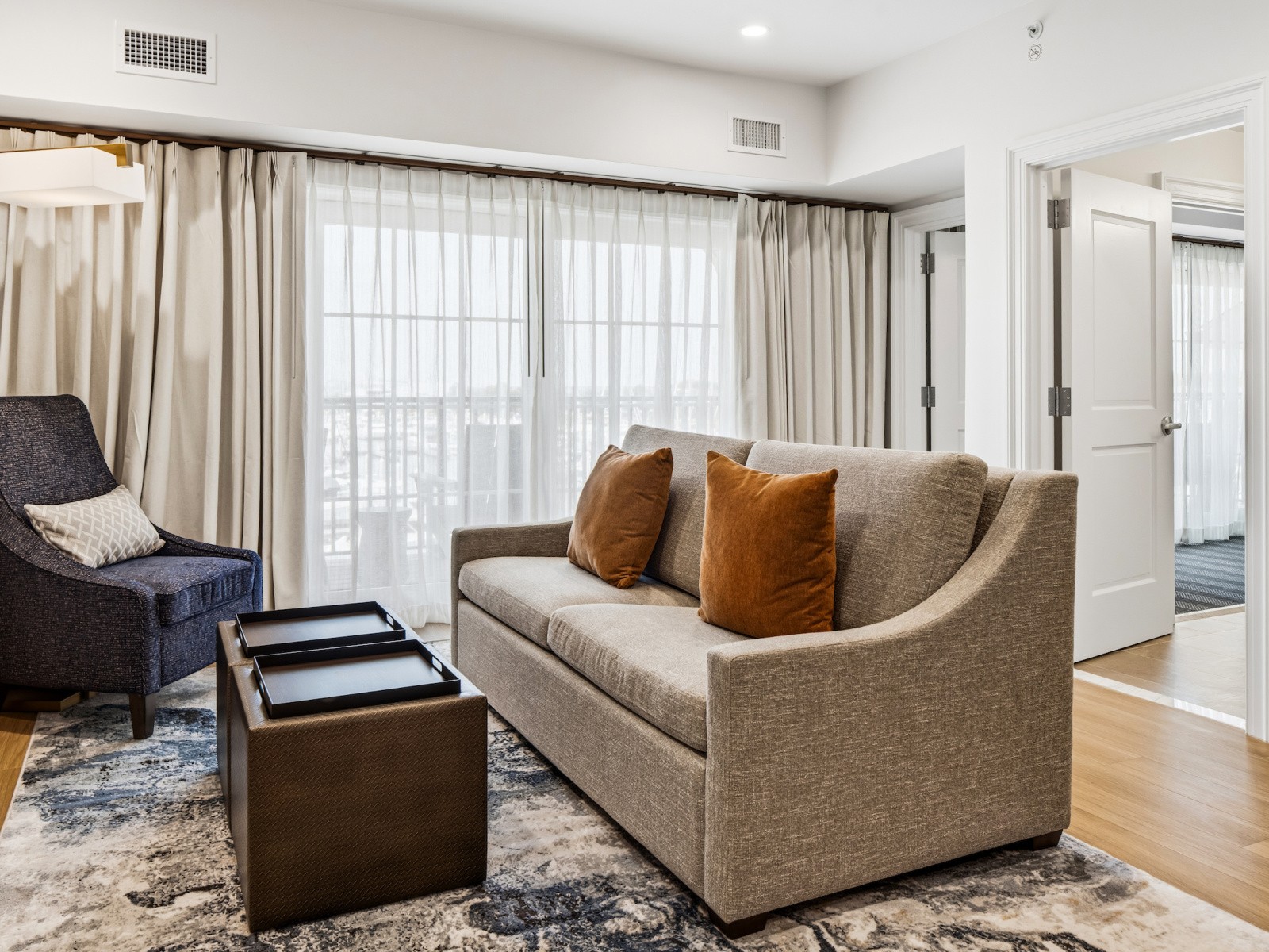 Harbor Suite living area at Wilson’s Cove with sofa, coastal furnishings and private balcony.